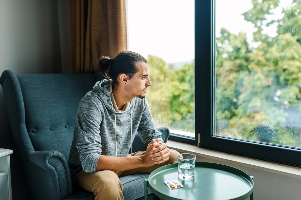 man looking out window in rehab