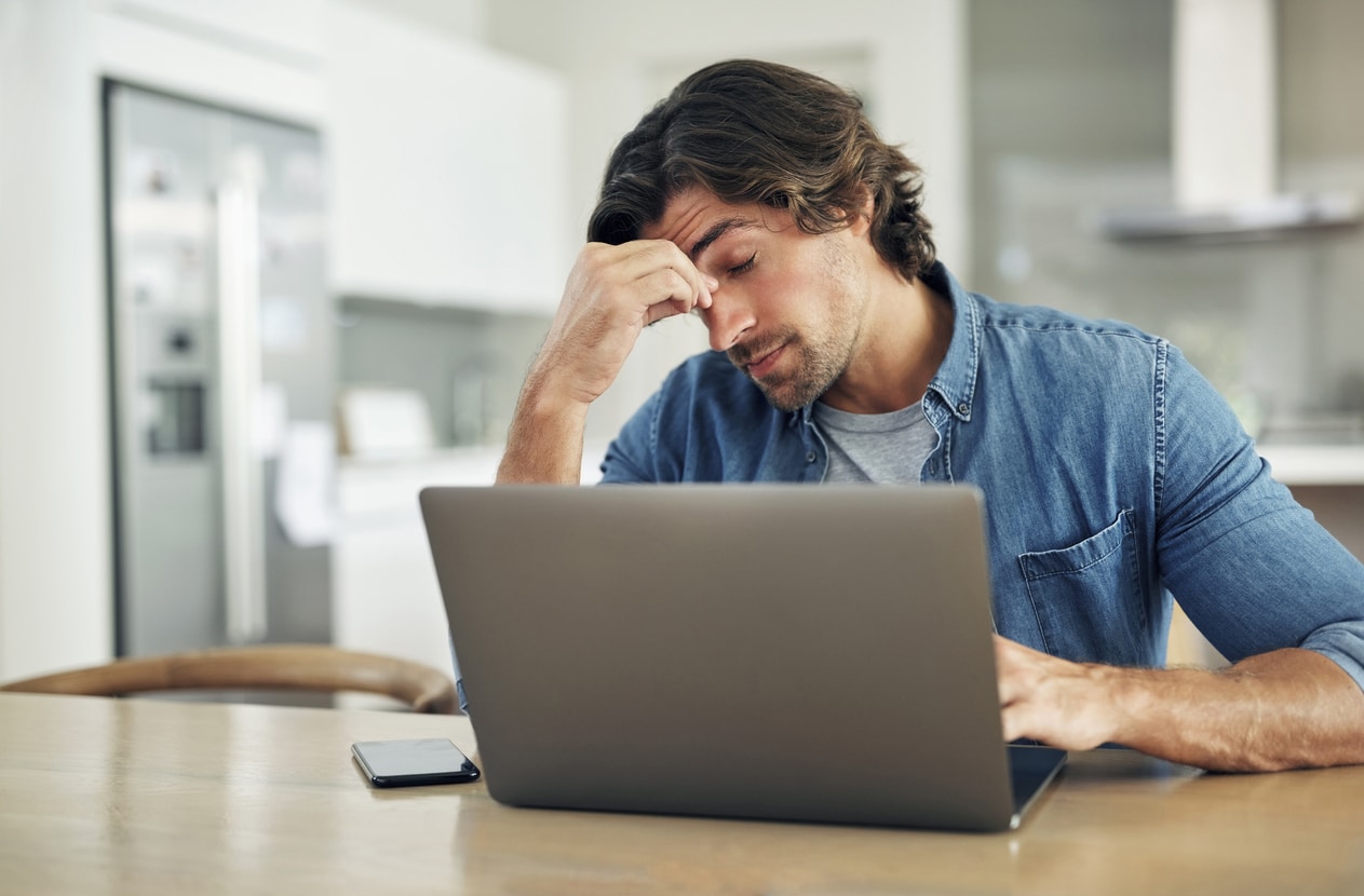 man rubbing his eyes frustrated and tired on computer