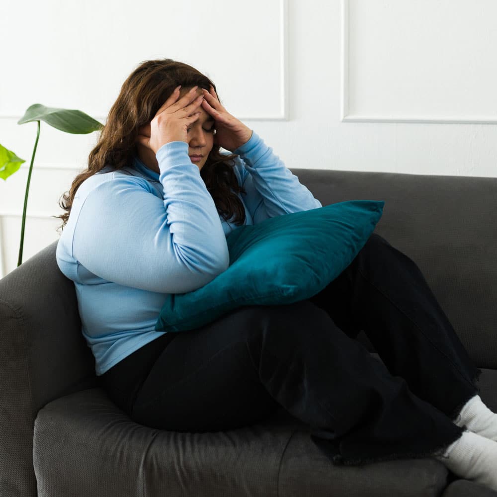 upset woman on couch with face in hands