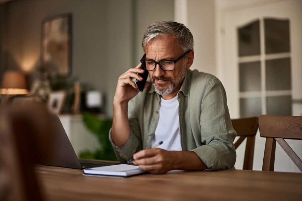 man looking at bills and paying over the phone