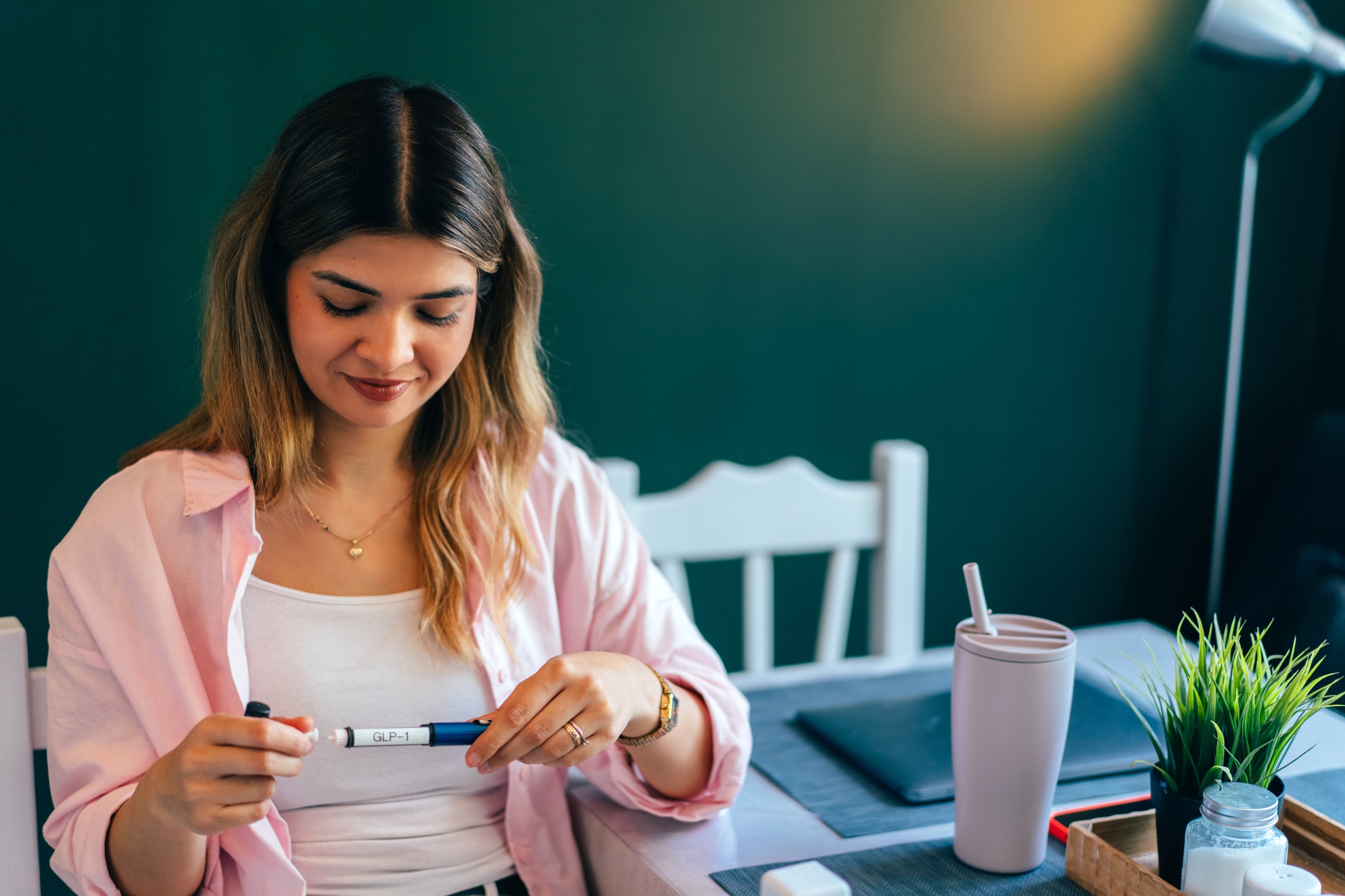Young woman preparing injectable diabetes or weight loss medication pen at home. Healthcare, self care, GLP-1 treatment and modern wellness concept.